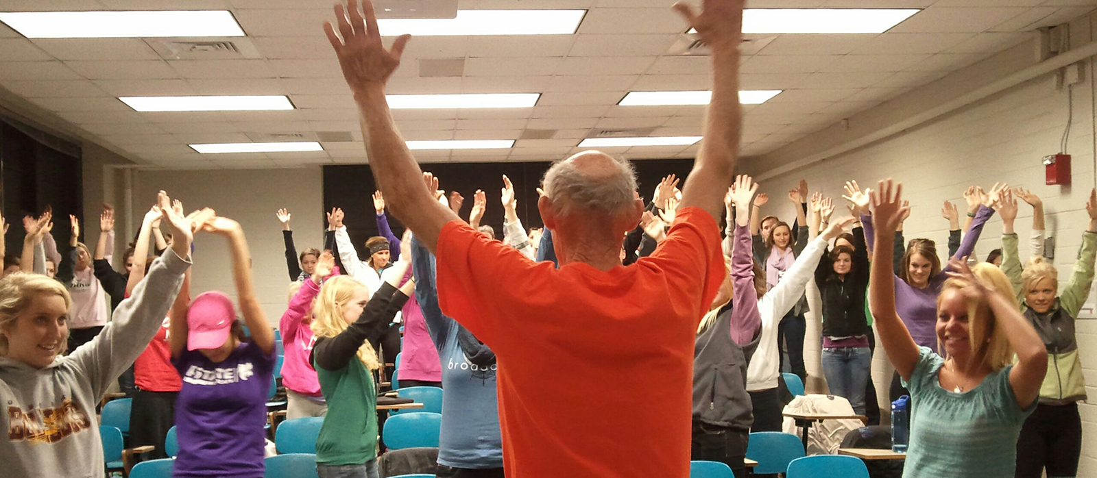 Participants at an event all standing with hands raised