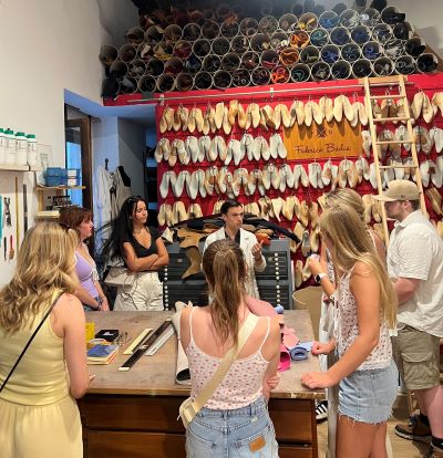 Studnts in a shoe maker shop surrounded by shoe forms in Italy.
