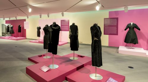 A wide view of the museum floor with forms dressed in a variety of black dresses from the collection.