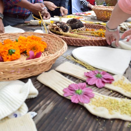 A table scape holding natural materials such as flowers and grass as hands work amongst the materials