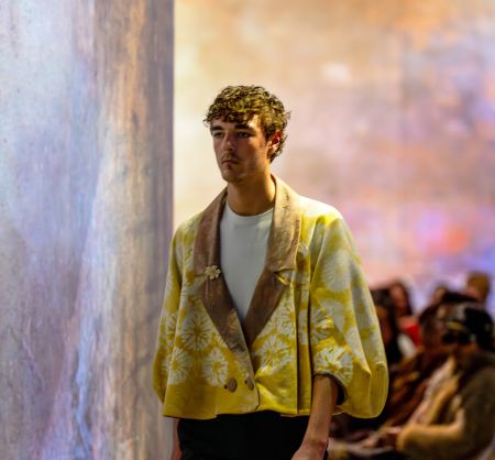 Student Model from waist up in a yellow top with a dark background