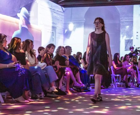 Student model walking through a seated audience with digital imagery in the background