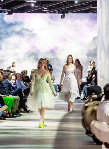student models moving through a seated crowd with digital imagery background