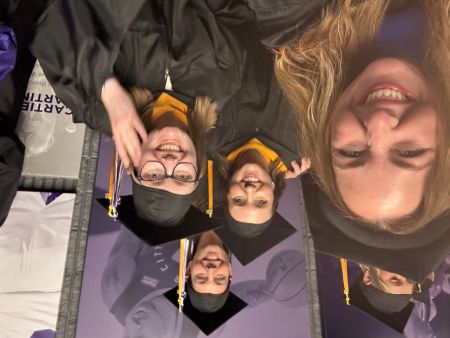 Master student posing for a selfie with Dr. Megan McCoy in cap and gowns at graduation.