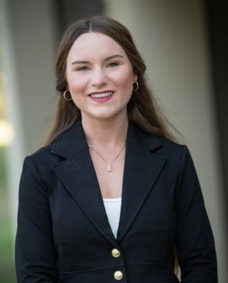 Headshot of Jordan Hofmann with a natural background.