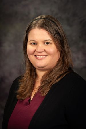 Headshot of Erin Gleason in a dark sweater and dark background
