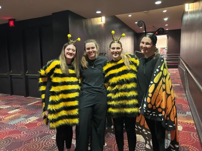 Four EHM students posing in a hotel hallway dress as bees and butterflies
