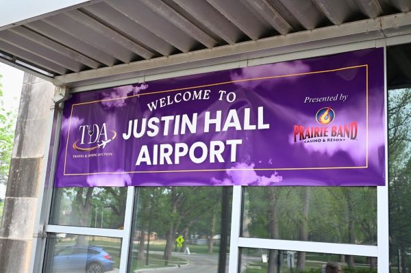 Travel and Dining themed banner on the outside of the building stating "Welcome to Justin Hall Airport" and Prairie Band Sponsorship logo