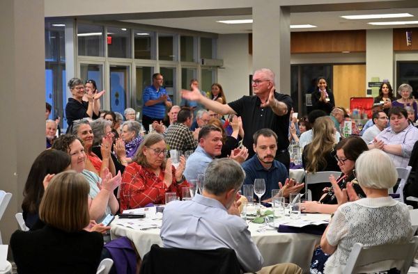 The image is of the audience and auction goers seated during live auction at round tables in Justin Hall's Hoffman Lounge