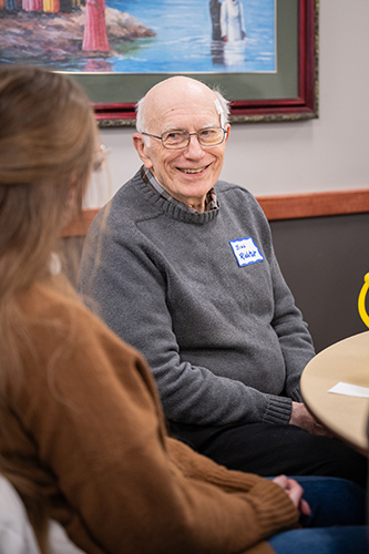 Senior adult with students at roundtable event