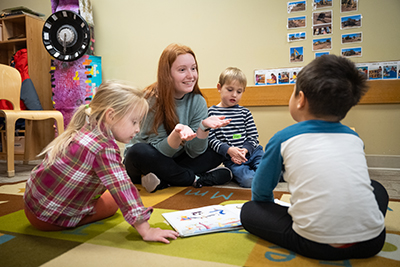 Pre-school teacher and children sitting on the floor