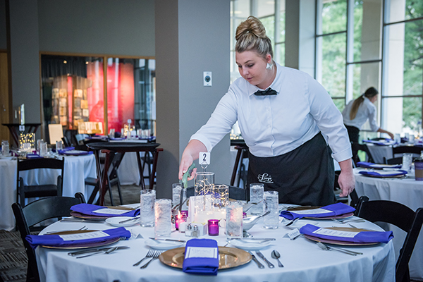 Student lighting candle in banquet preparation