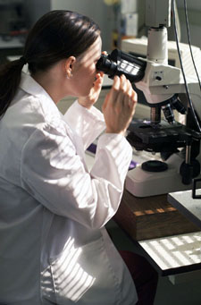 Photo of a woman looking into a microscope