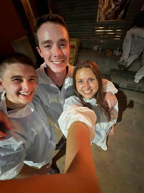 2 males and 1 female smile at the camera in front of a food truck